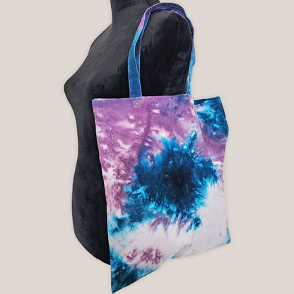 Tie-dye tote bag with blue and purple patterns on a plain background