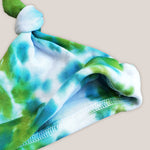 A green and teal tie dye organic baby hat.