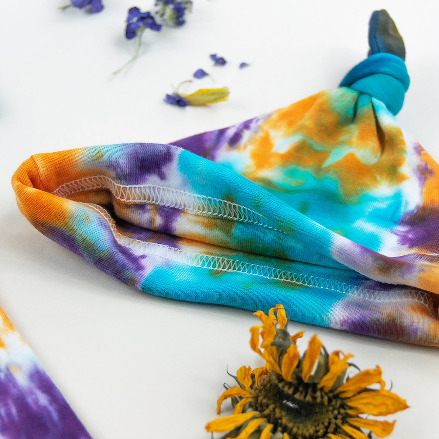 Teal, purple, and orange tie dye organic cotton bodysuit and baby hat set by Akasha Sun.