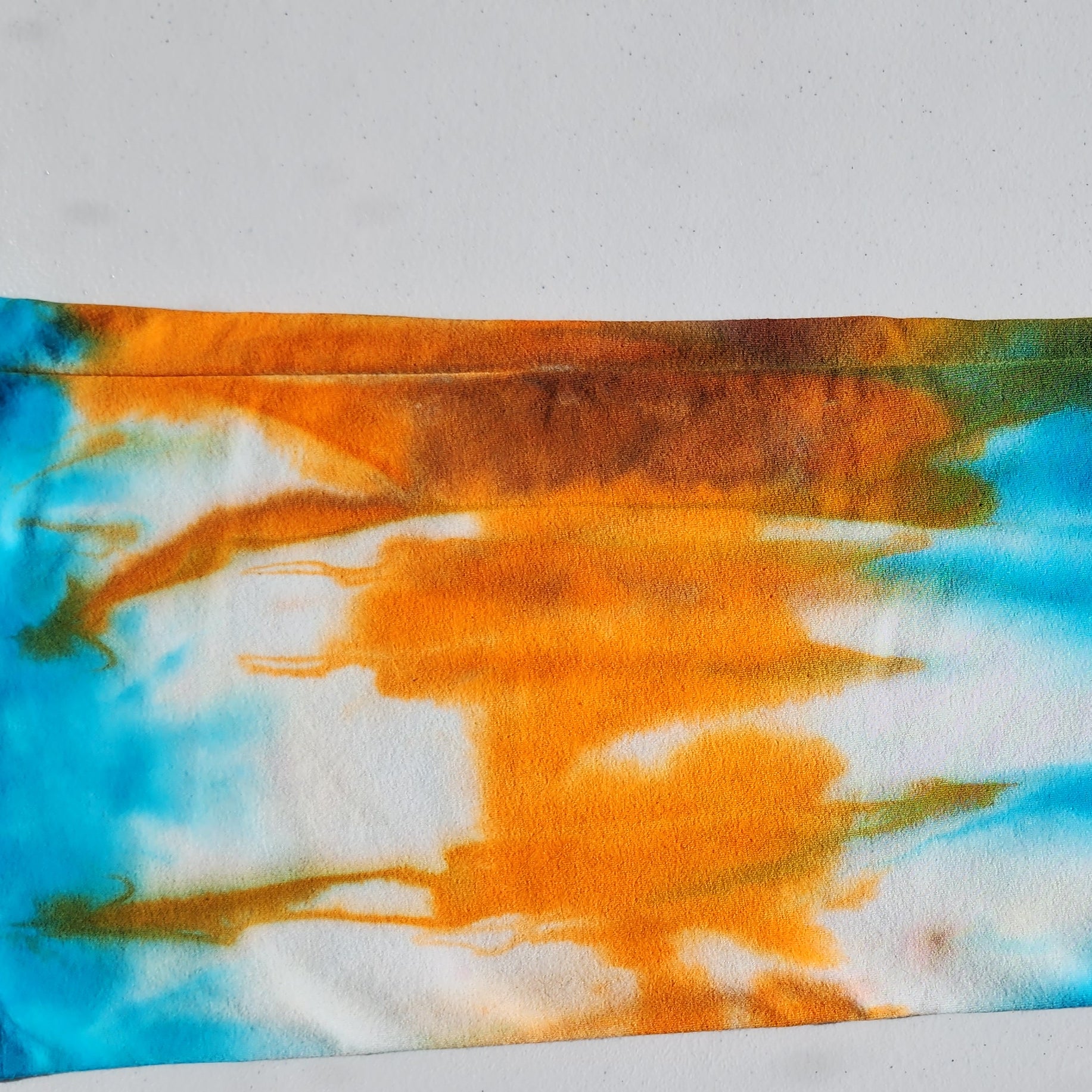 Tie-dye fabric with orange and blue patterns on a white background
