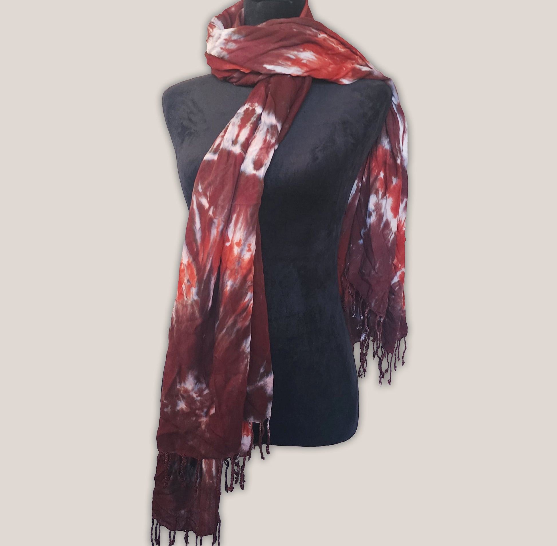 Red and brown tie-dye scarf on a mannequin against a beige background