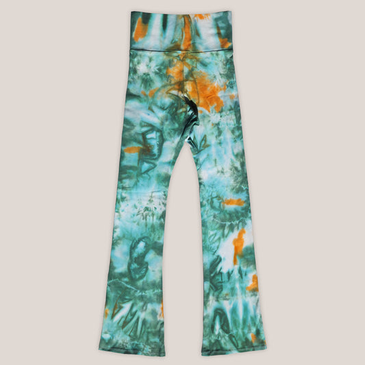 Tie dye teal and orange flare leggings on a beige background.