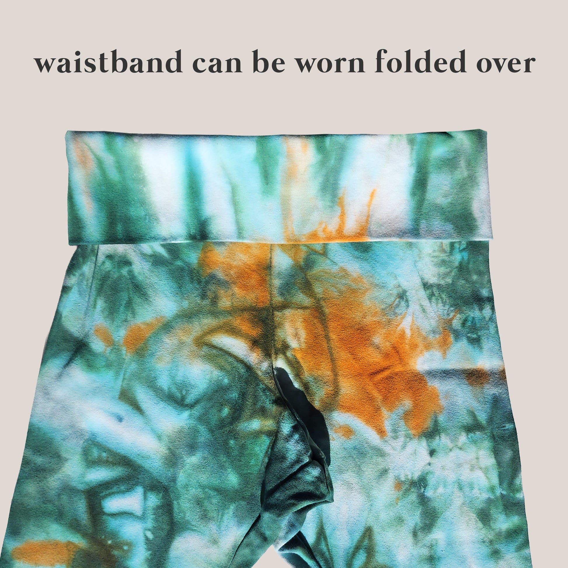 Tie-dye waistband with text indicating it can be worn folded over on a beige background