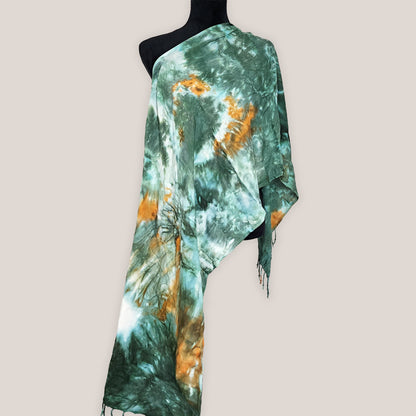 Green and orange tie-dye scarf on a mannequin against a plain background