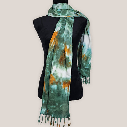 Tie-dye scarf with green and orange pattern on a mannequin against a beige background