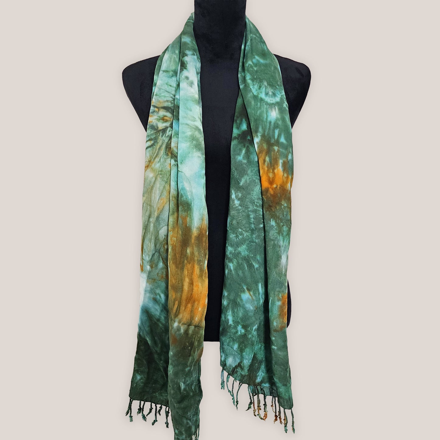 Green and orange tie-dye scarf on a mannequin against a white background
