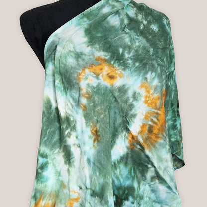 Green and orange tie-dye fabric on a mannequin against a beige background