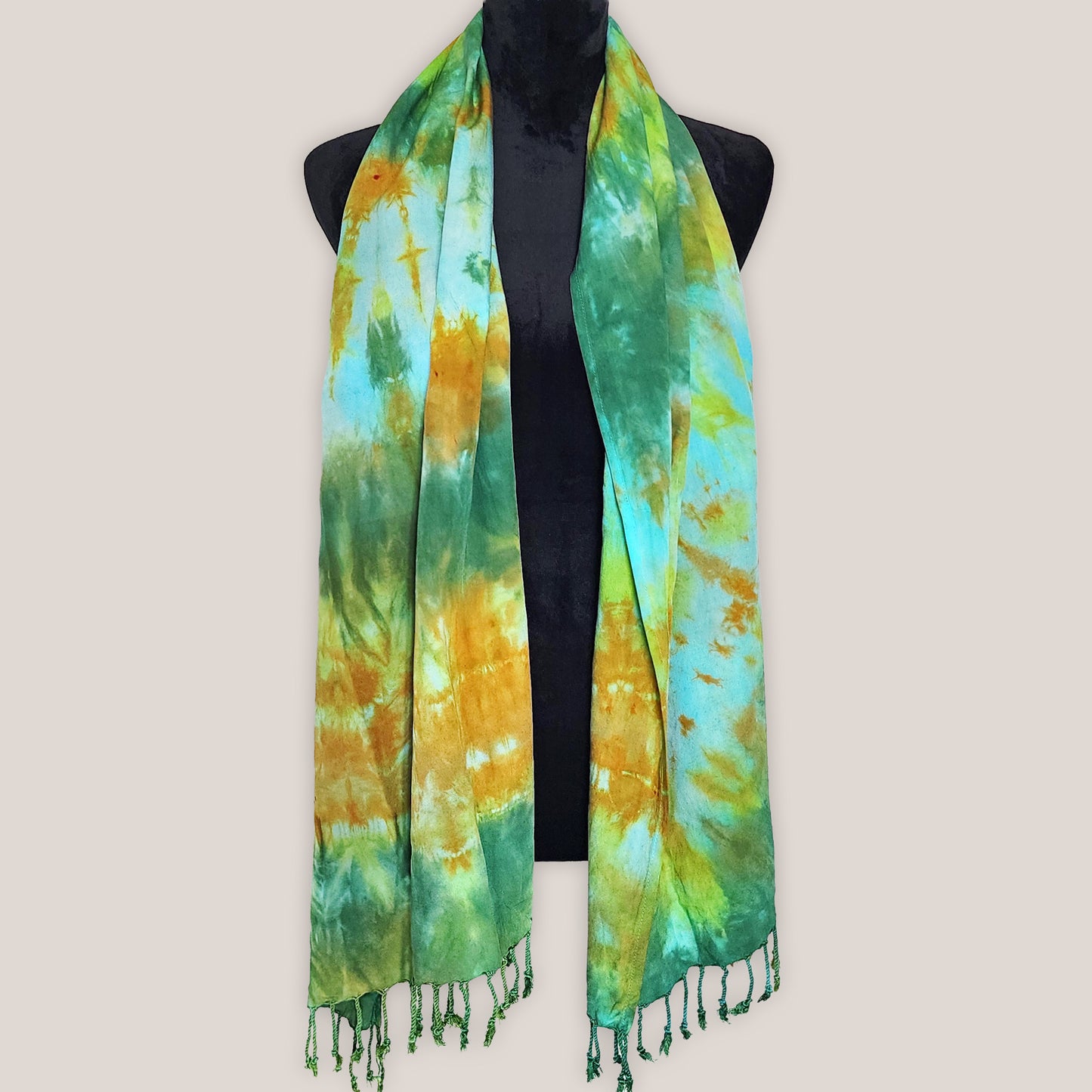 Tie-dye scarf with green and yellow pattern on a mannequin against a beige background