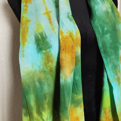 Tie-dye scarf with green and yellow patterns on a neutral background