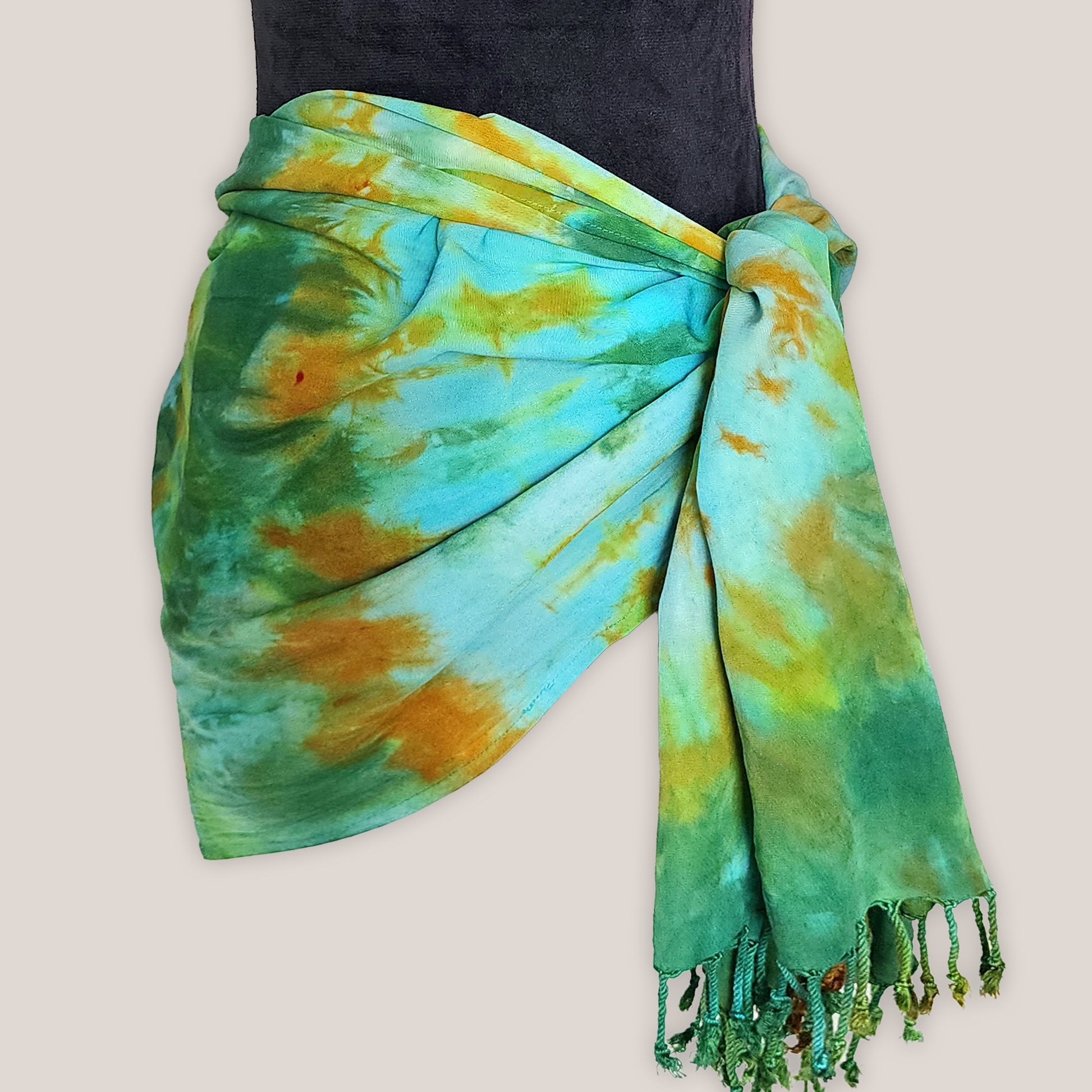 Tie-dye scarf with green and orange patterns on a beige background