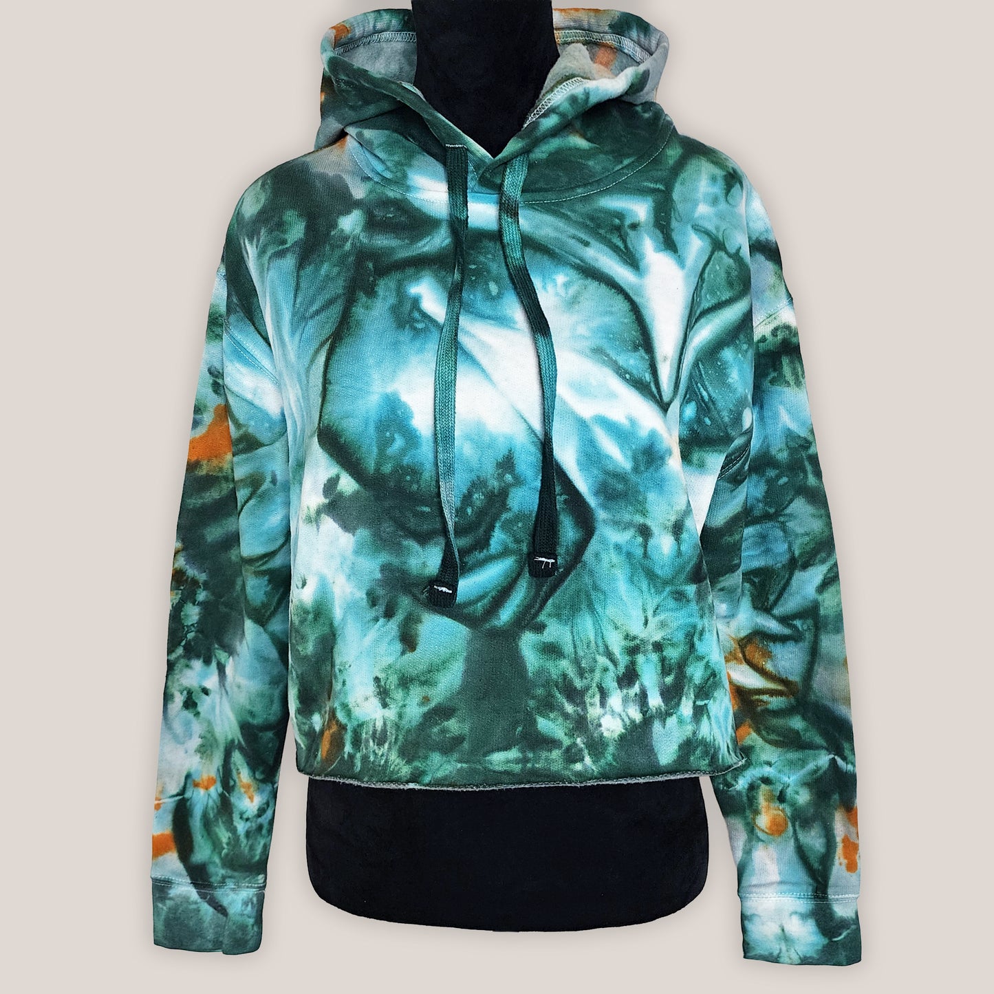 Green and orange patterned hoodie on a mannequin against a beige background