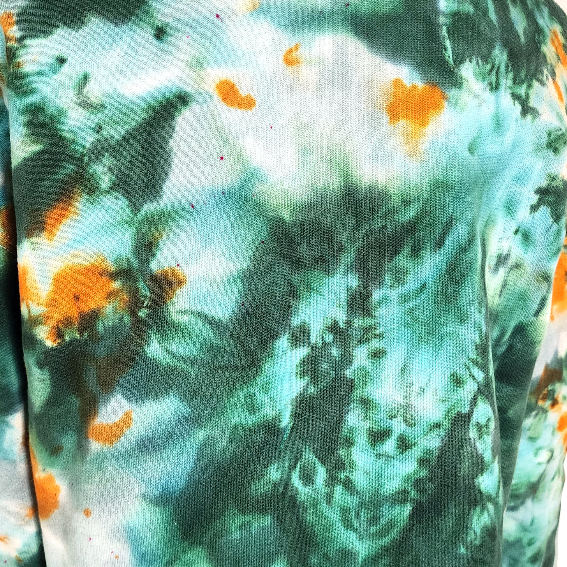 Close-up of a tie-dye shirt with green, orange, and white patterns.