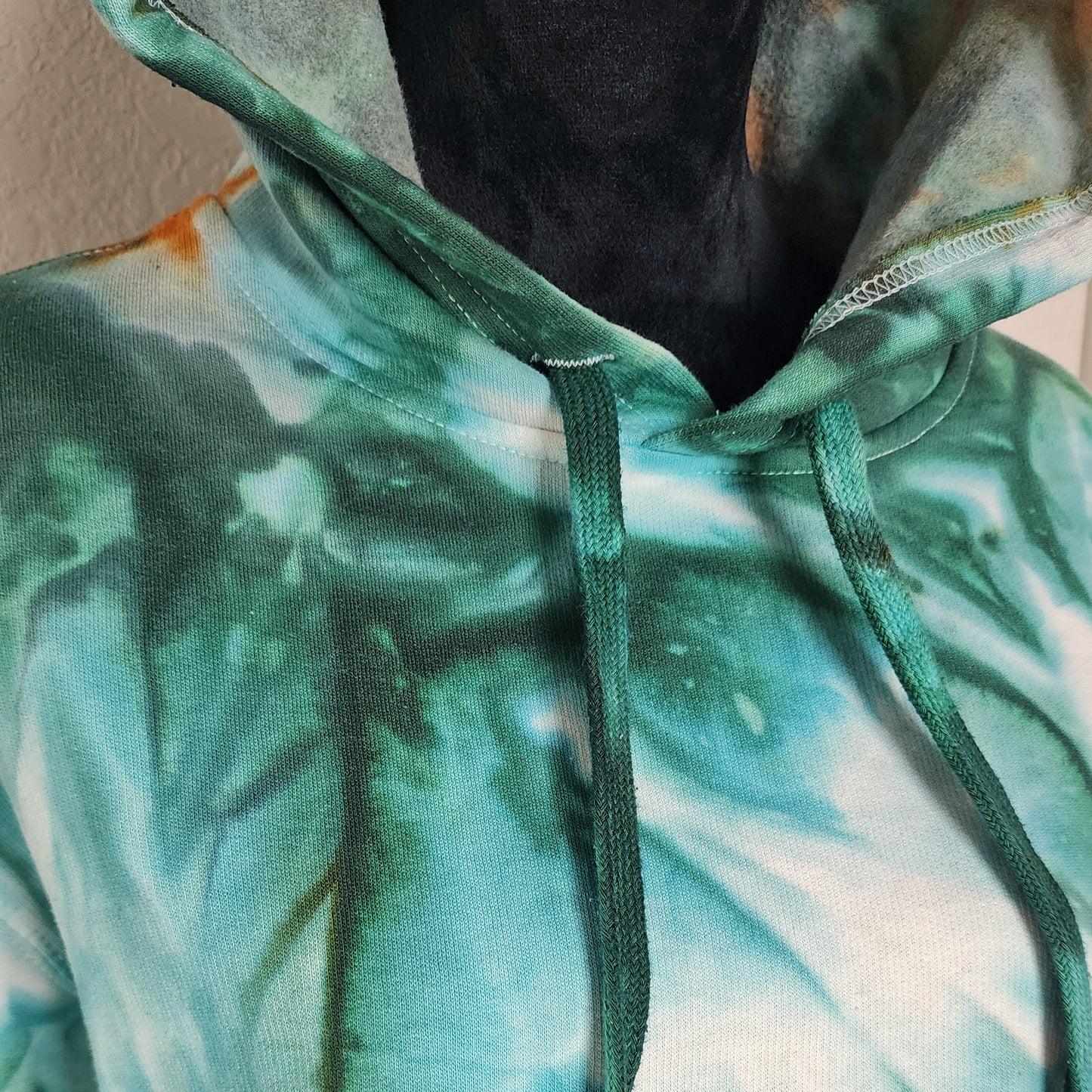 Close-up of a green and white tie-dye hoodie with a blurred background