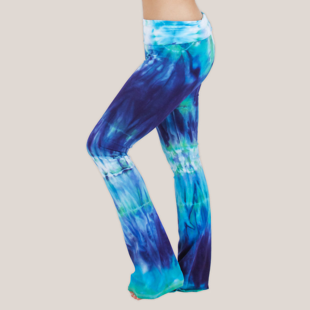 Woman wearing the Galapagos Islands tie dye yoga pants that features hand-dyed hues of navy blue, teal, and aqua.  These pants include a fold over waistband that is also comfortable as maternity wear.