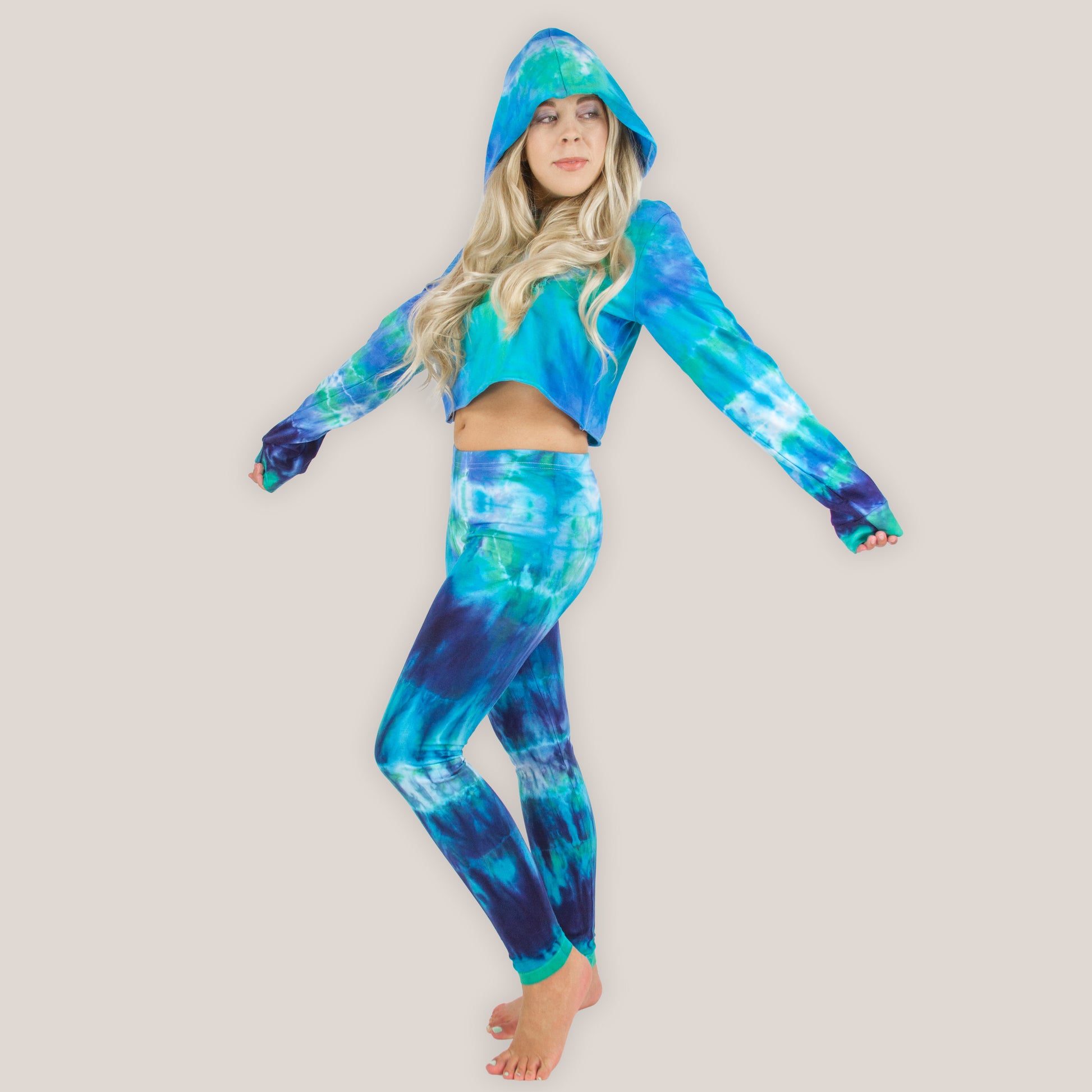 Person wearing a blue and green tie-dye hoodie and leggings set on a beige background
