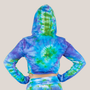 Woman wearing the Grenada tie dye hoodie crop top featuring hand-dyed hues of aqua, purple, and green by Akasha Sun