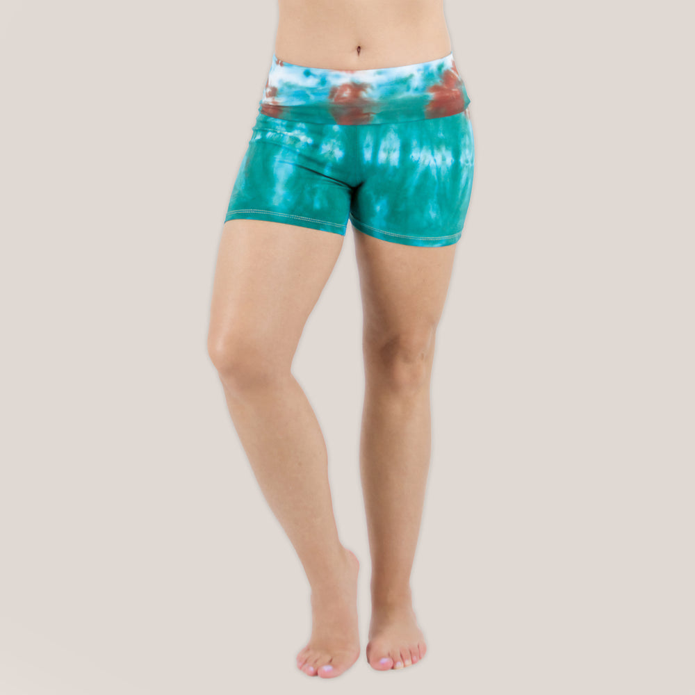 Woman wearing Akasha Sun Kiowa fold over tie dye shorts in teal and brown.