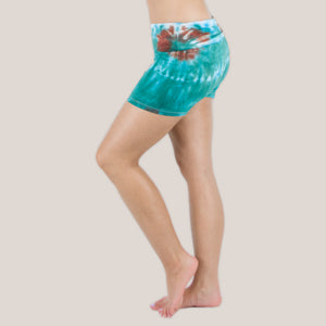 Woman wearing Akasha Sun Kiowa fold over tie dye shorts in teal and brown.