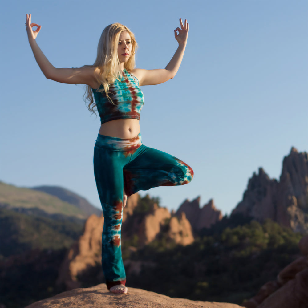 Woman standing in Garden of the Gods wearing Kiowa tie dye yoga pants with a fold over waistband in the colors teal and copper by Akasha Sun