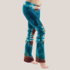 Woman standing in Garden of the Gods wearing Kiowa tie dye yoga pants with a fold over waistband in the colors teal and copper by Akasha Sun