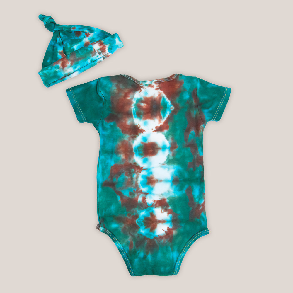 A teal and copper tie dye onesie and baby hat set by Akasha Sun.