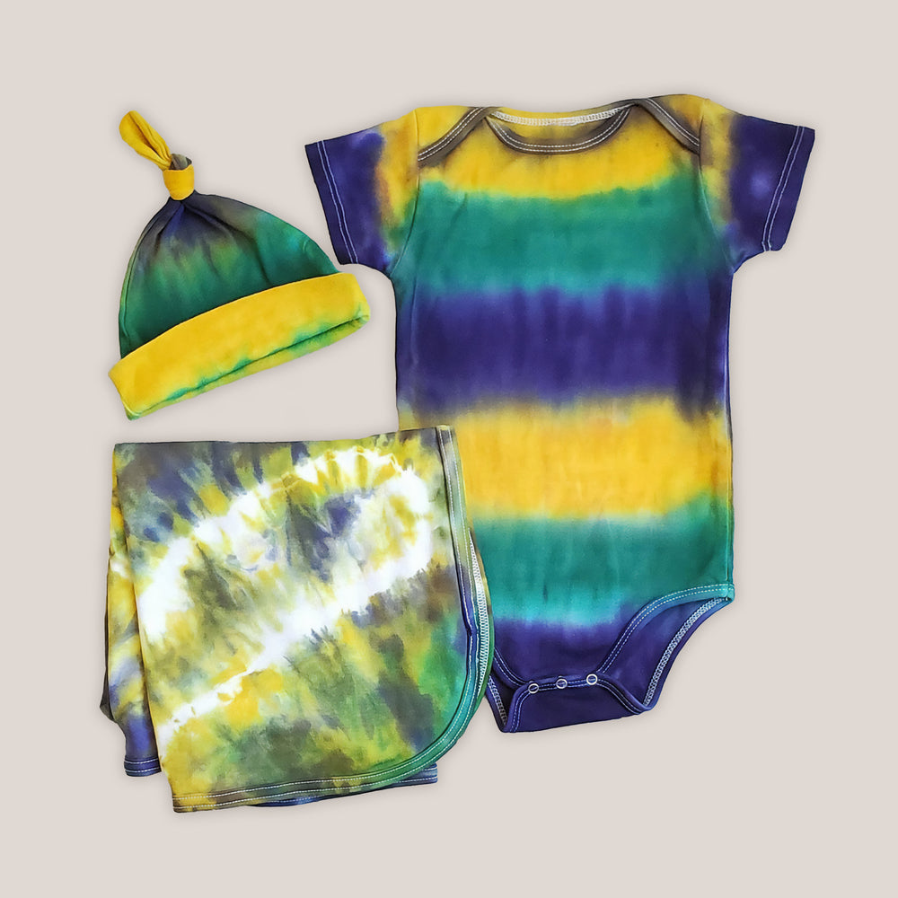 A tie dye organic baby set including a baby blanket bodysuit, hat, and blanket in Mardi Gras colors.