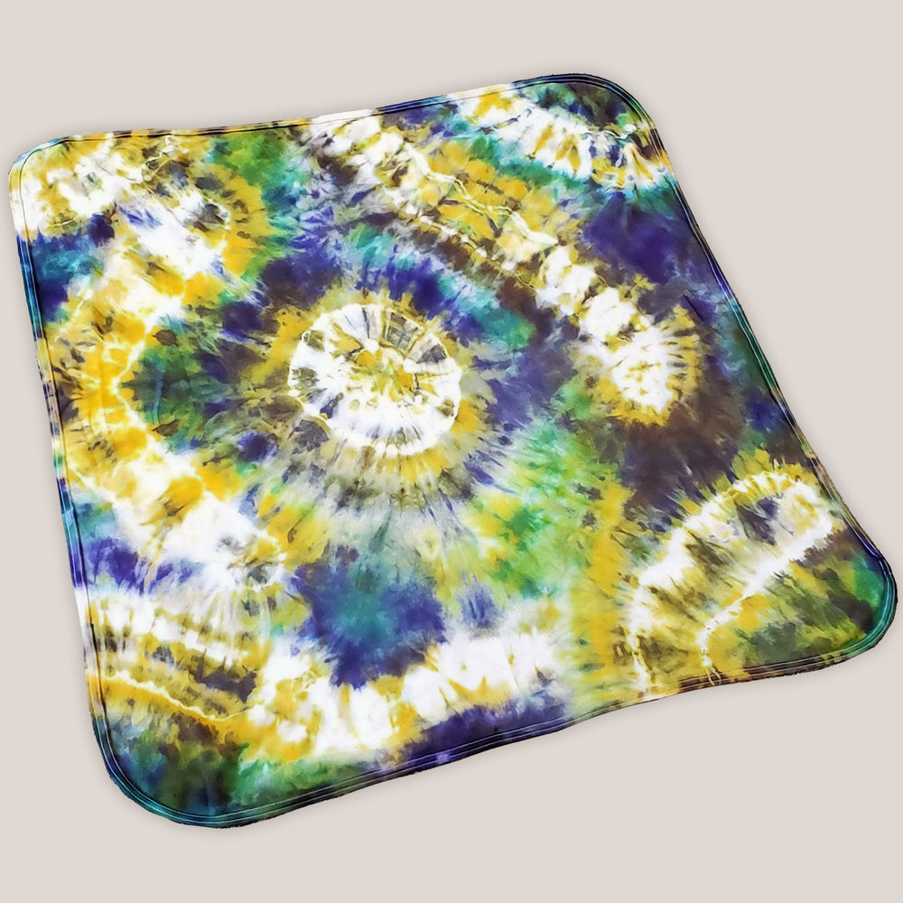 A tie dye organic baby set including a baby blanket bodysuit, hat, and blanket in Mardi Gras colors.