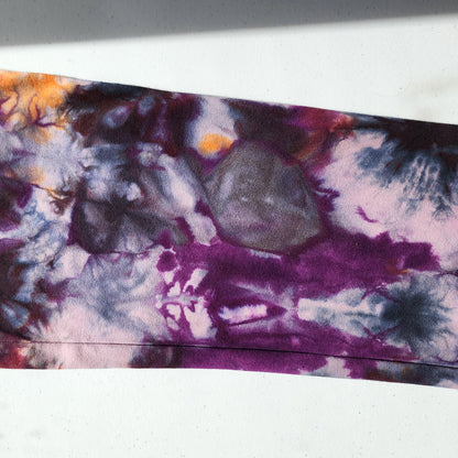 Close-up of a tie-dye pattern with purple, orange, and gray colors on a white background.