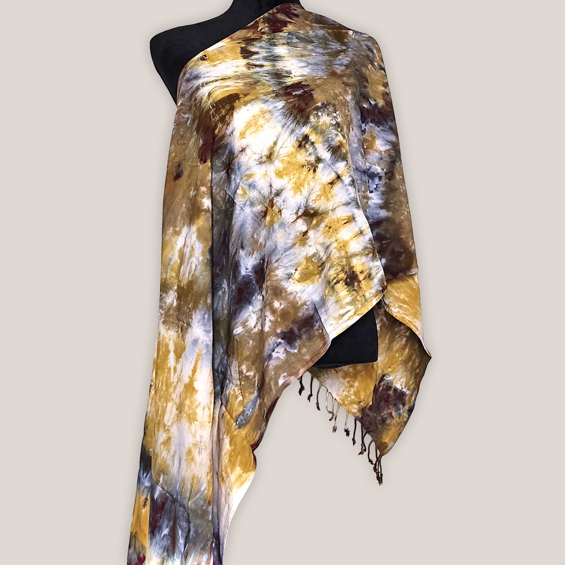 Tie-dye scarf with gold, brown, and black patterns on a mannequin against a plain background
