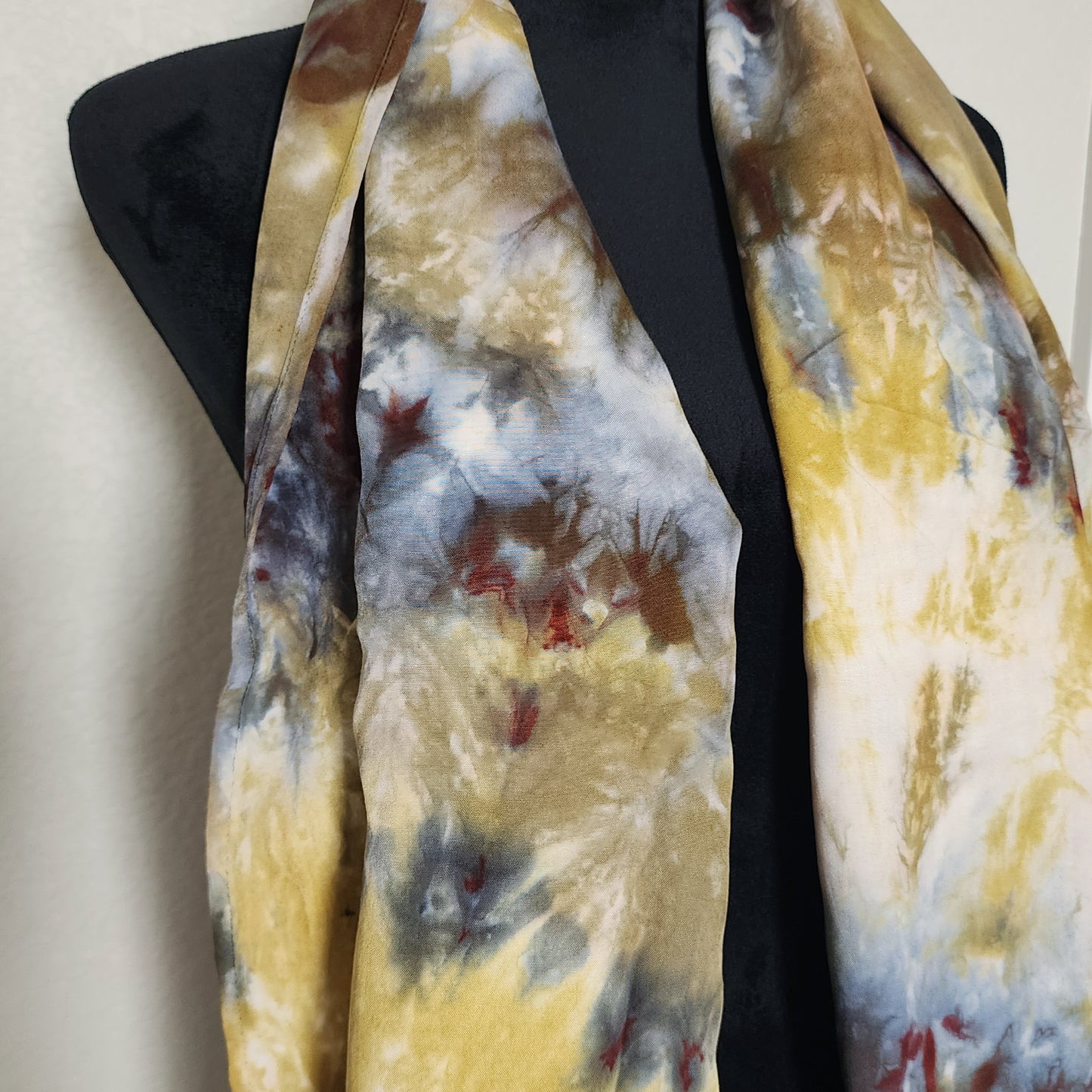 Scarf with abstract pattern draped over a black dress form on a light background