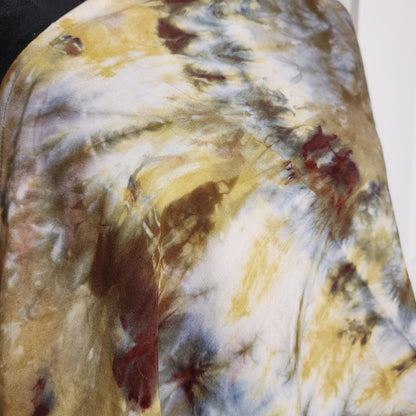 Abstract tie-dye pattern with yellow, brown, and red colors on a fabric surface.