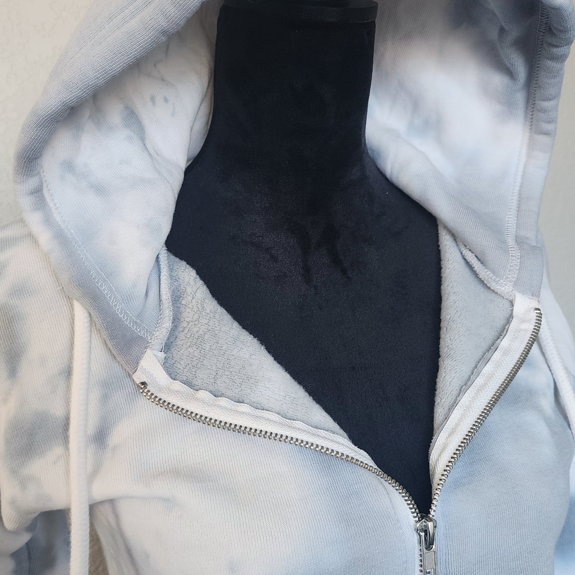 Close-up of a gray hoodie with a zipper, showing the inside lining.