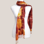 A rust orange tie dye scarf with fringe by Akasha Sun