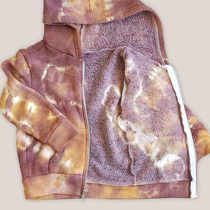 A rust tie dye children's jacket with fleece lining, pockets, and hood.