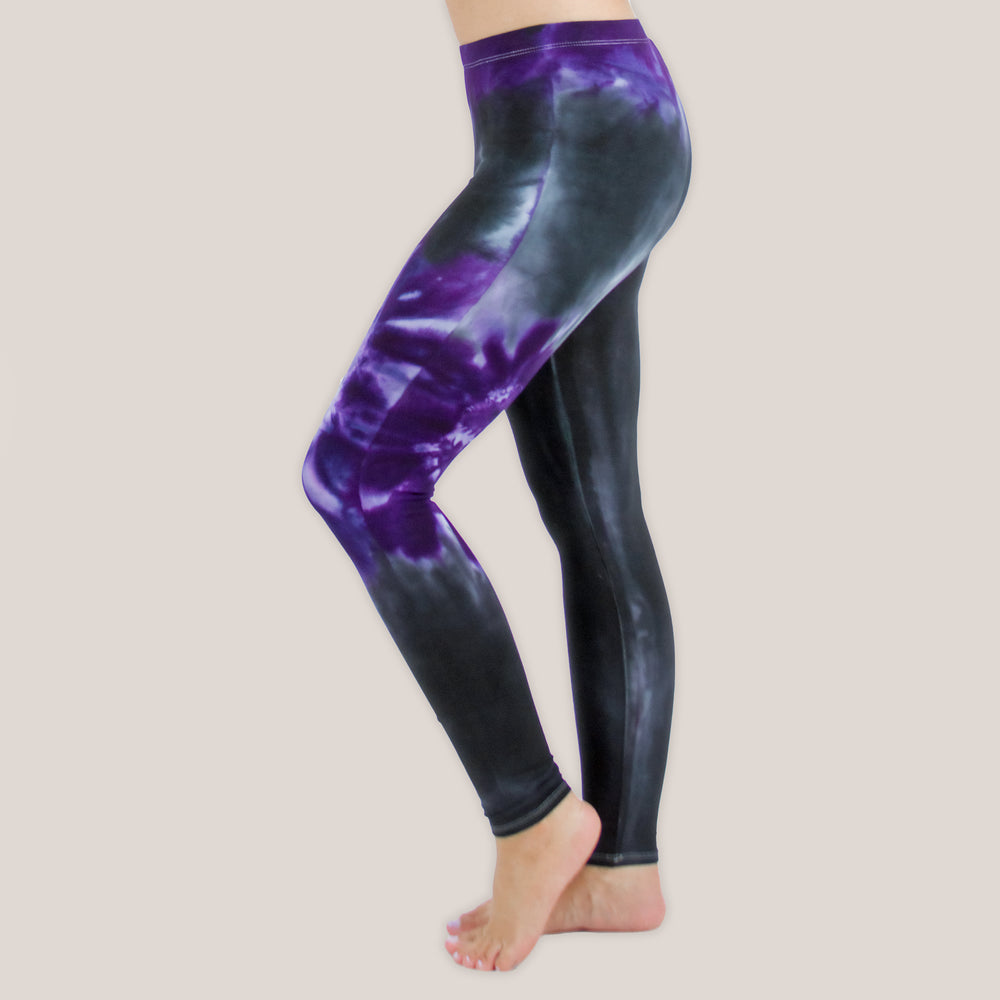 Woman wearing a pair of Akasha Sun purple chakra tie dye leggings made of sustainable cotton.