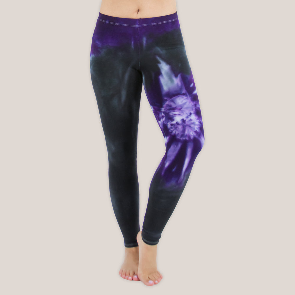 Woman wearing a pair of Akasha Sun purple chakra tie dye leggings made of sustainable cotton.