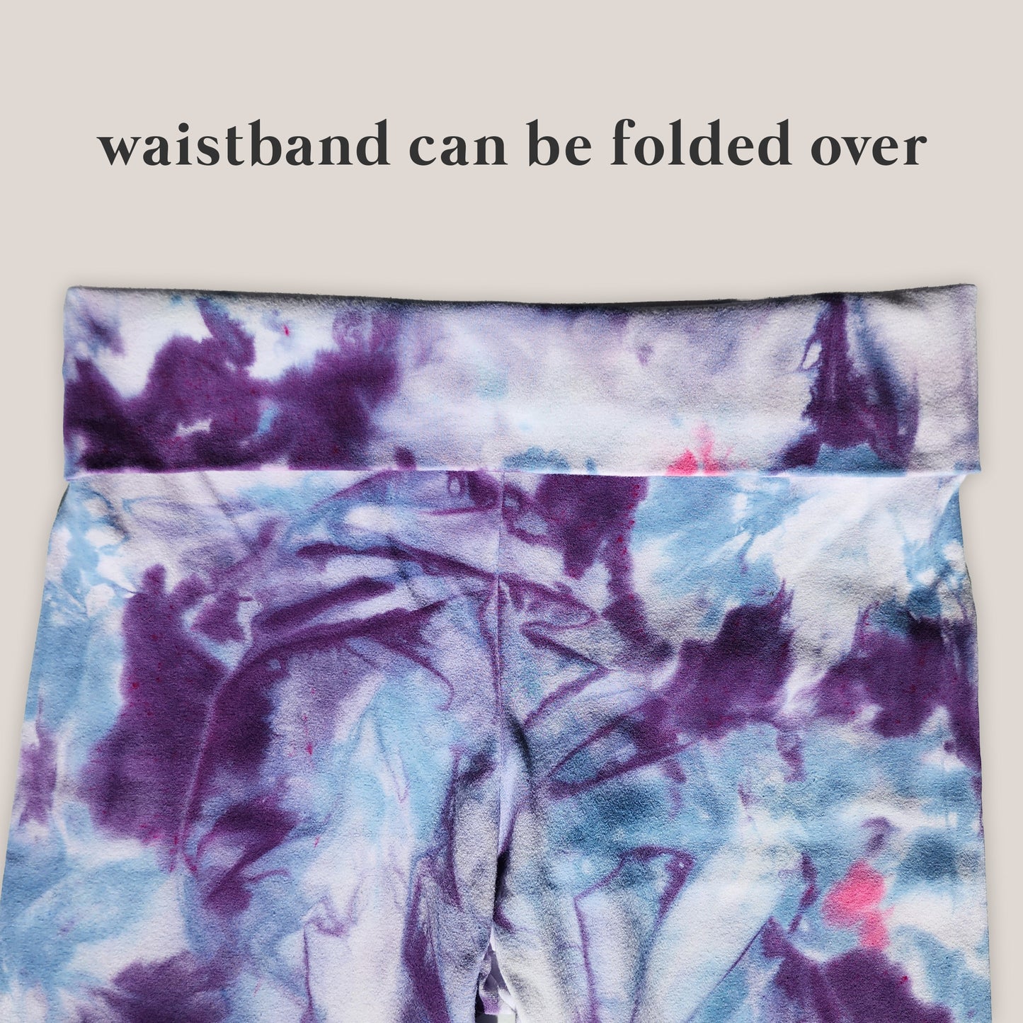 Tie-dye yoga pants with a folded waistband on a light background