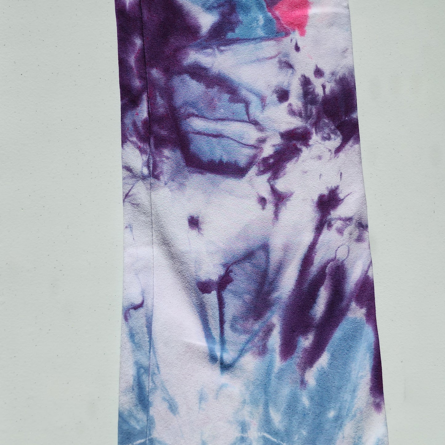 Tie-dye fabric with purple, blue, and white pattern on a light gray background