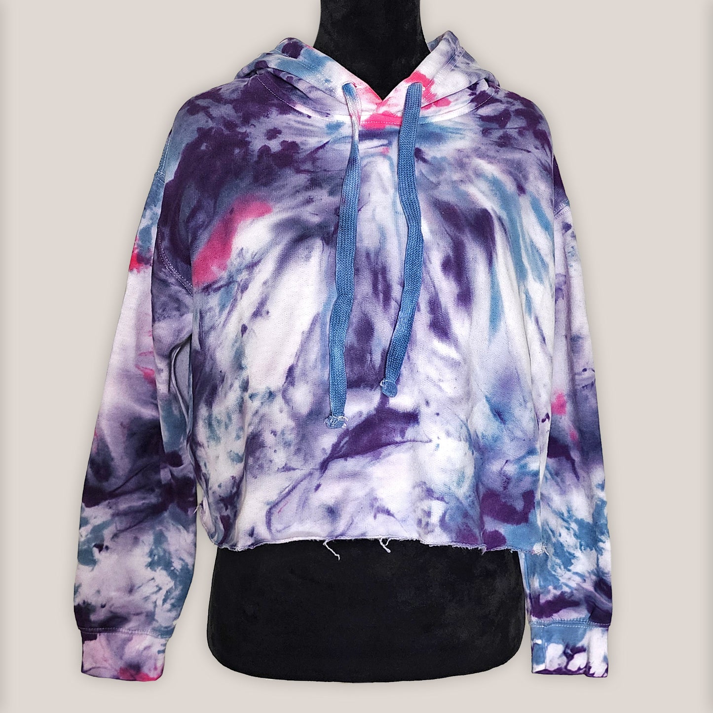 Multicolored tie-dye hoodie on a mannequin against a plain background