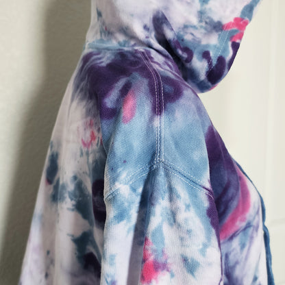 Close-up of a tie-dye fabric with blue, pink, and purple colors on a neutral background.