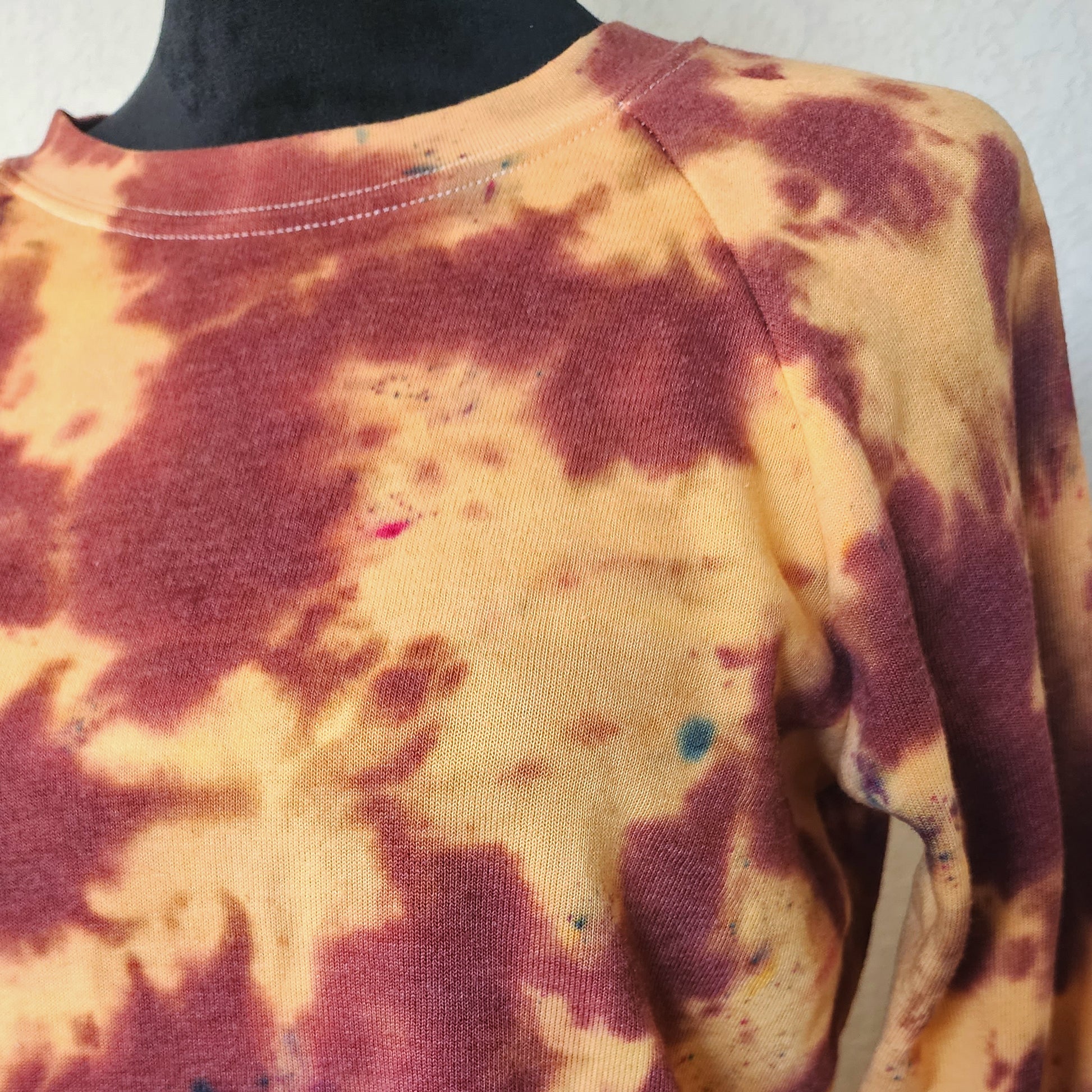 Tie-dye shirt with brown and orange patterns on a mannequin.