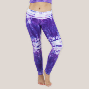 Woman wearing the Saint-Tropez tie dye leggings that feature a fold over waistband.  The colors in these pants include purple, pink, and white.