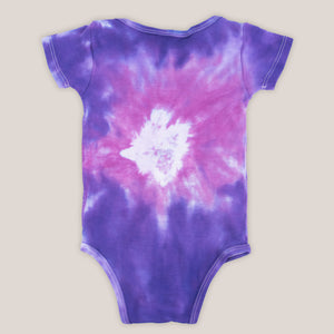 Pink and purple tie dye organic baby set that includes a baby blanket, onesie, and baby hat.