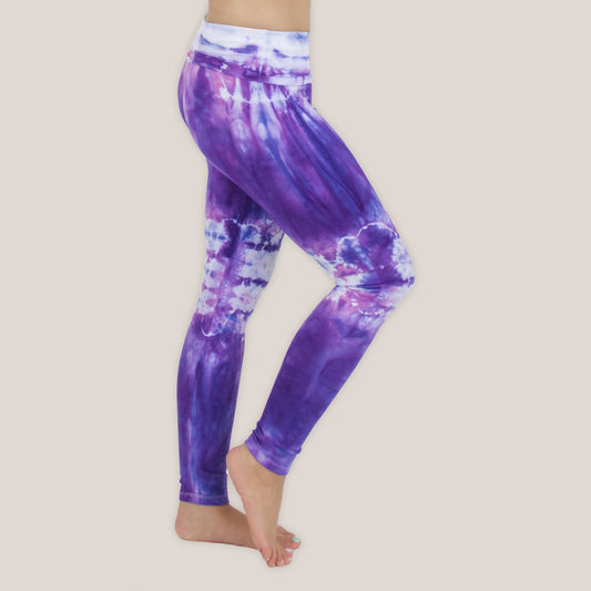 Woman wearing the Saint-Tropez tie dye leggings that feature a fold over waistband.  The colors in these pants include purple, pink, and white.
