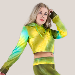 Woman wearing a tie dye hoodie crop top in green, yellow, and teal by Akasha Sun.