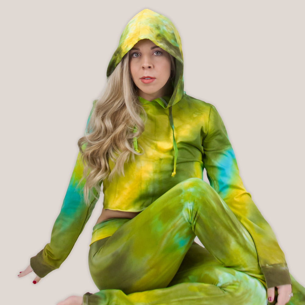 Woman wearing a tie dye hoodie crop top in green, yellow, and teal by Akasha Sun.