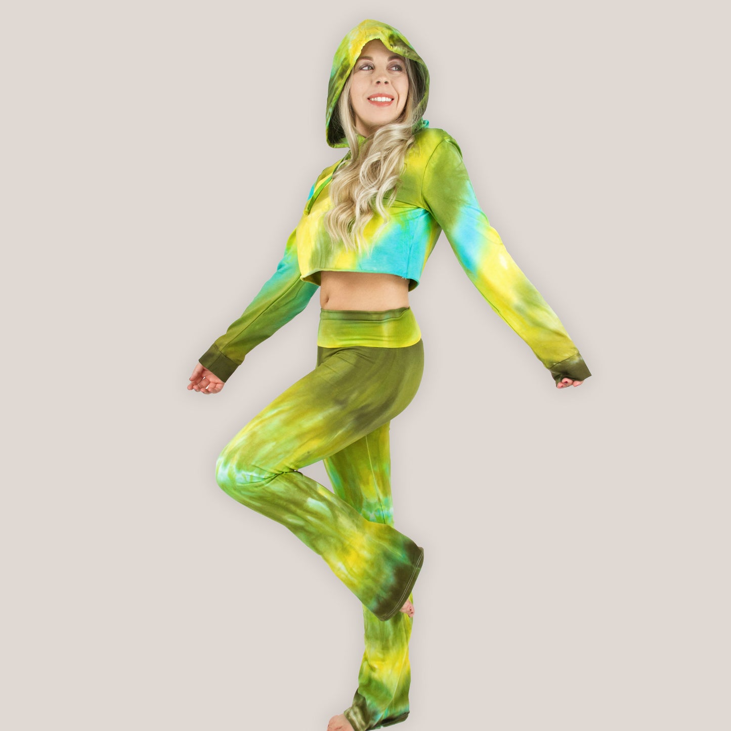 Woman wearing a green and yellow tie-dye outfit on a plain background
