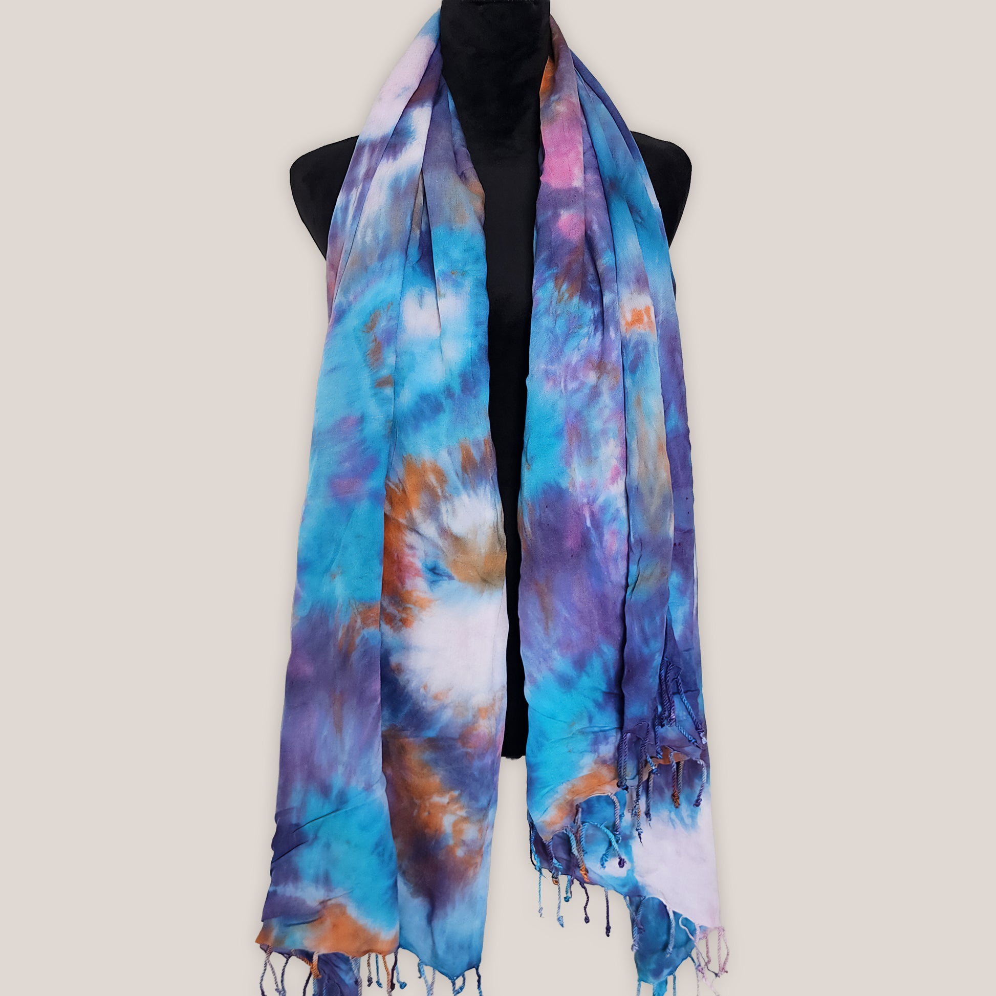 Colorful tie-dye scarf on a mannequin against a plain background