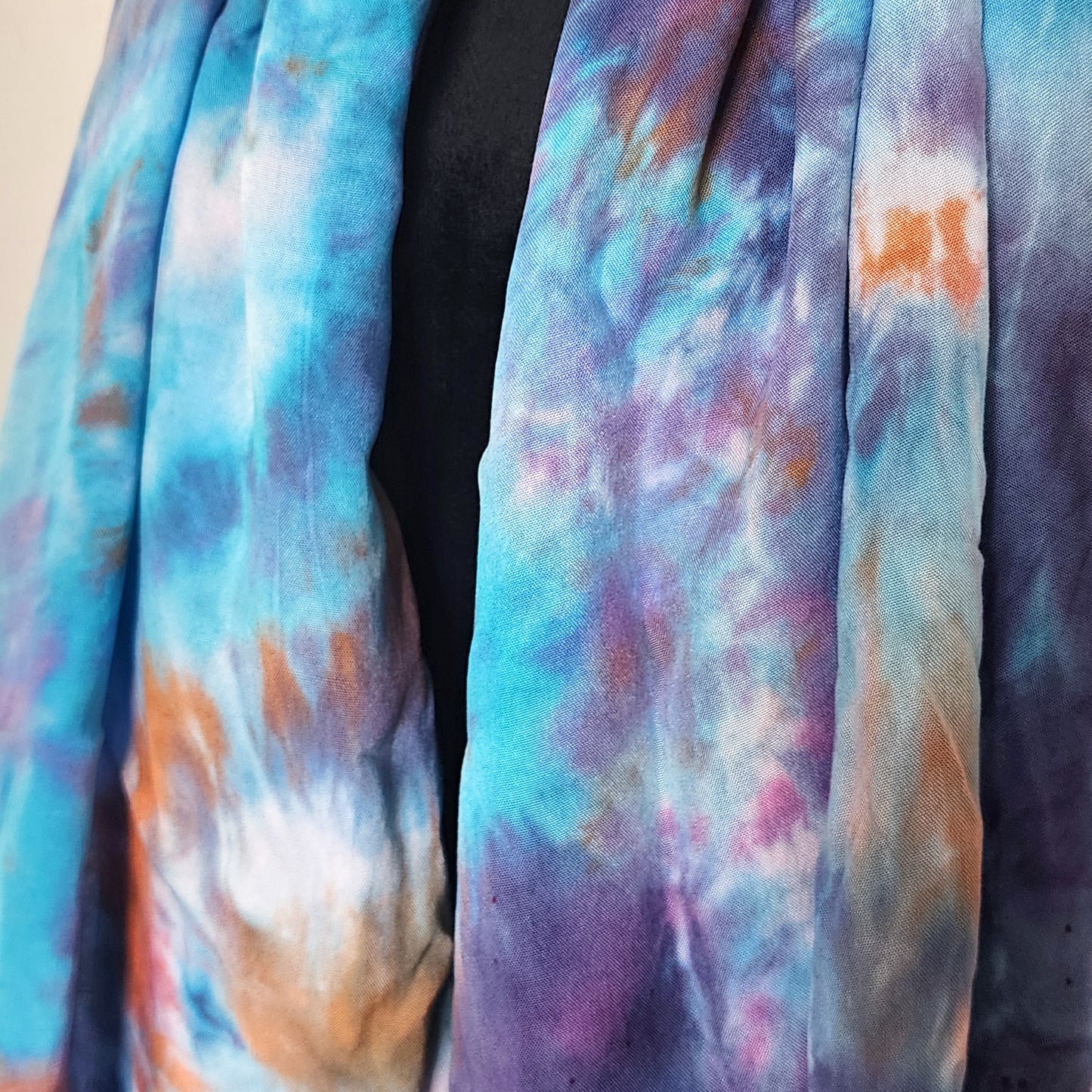 Multicolored tie-dye fabric with shades of blue, purple, and orange.