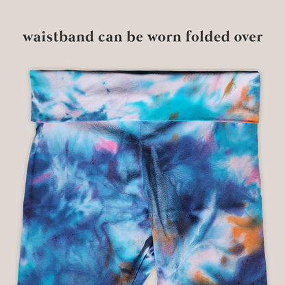 Colorful tie-dye leggings with a waistband that can be folded over on a beige background.
